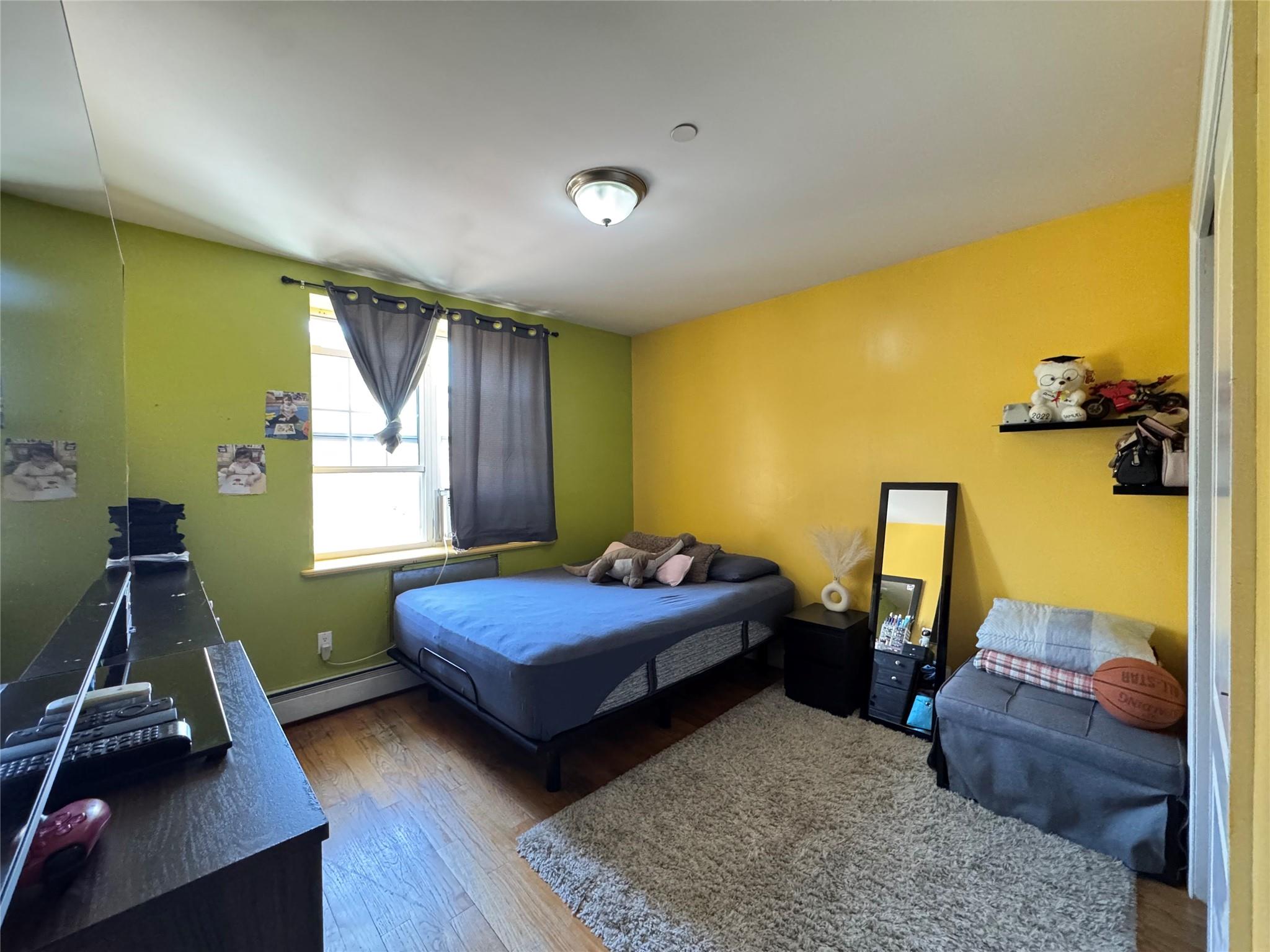 53-12 102nd Street Queens, NY 11368 - Photo 7 of 8 a bedroom with a bed and wooden floor