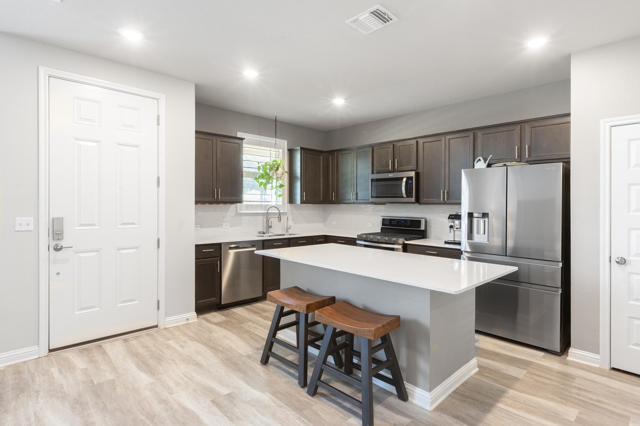 7801 Frida Bend Austin, TX 78744 - Photo 8 of 26 A contemporary kitchen showcasing dark wood cabinetry, stainless steel appliances, and a central island with bar seating.