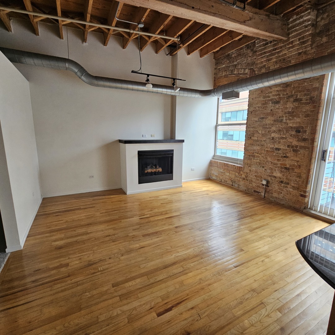 420 South Clinton Street, Unit 607 Chicago, IL 60607 - Photo 2 of 11 a view of empty room with wooden floor and fireplace