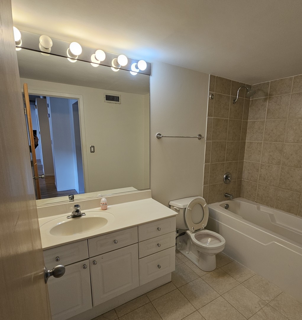 420 South Clinton Street, Unit 607 Chicago, IL 60607 - Photo 8 of 11 a spacious bathroom with a double vanity sink a toilet and a mirror