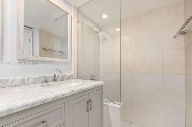 a bathroom with a granite countertop sink a mirror and a shower