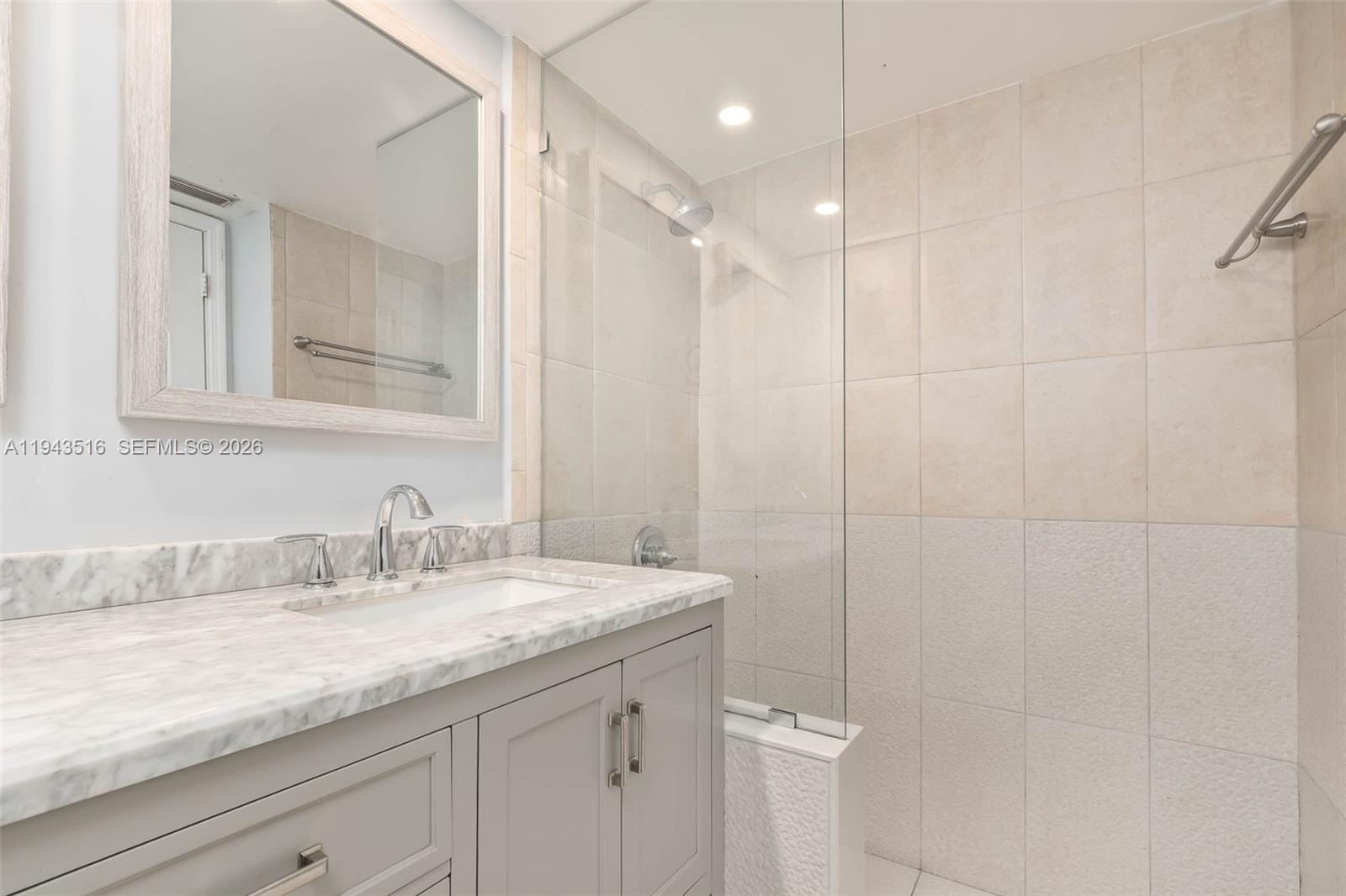 7324 Southwest 82nd Street, Unit B108 Miami, FL 33143 - Photo 12 of 17 a bathroom with a granite countertop sink a mirror and a shower