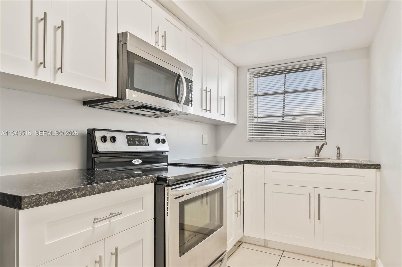 7324 Southwest 82nd Street, Unit B108 Miami, FL 33143 - Photo 8 of 17 a kitchen with granite countertop white cabinets stainless steel appliances and sink