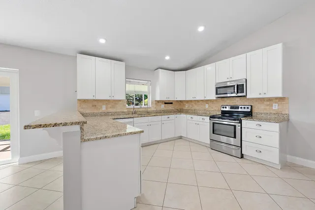 a kitchen with granite countertop white cabinets and appliances