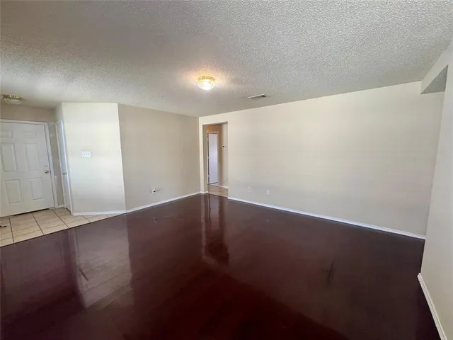 an empty room with wooden floor and windows with curtains