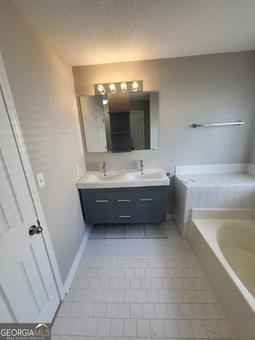 a en suite bathroom with a tub sink and mirror