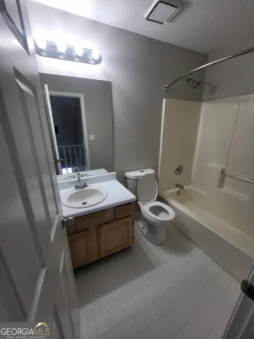a bathroom with a granite countertop sink a toilet a mirror and bathtub
