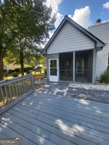 a front view of house with deck outdoor seating and covered with trees