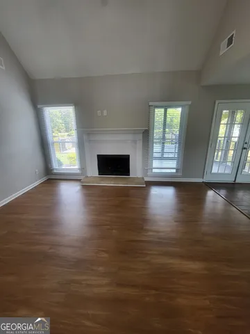 an empty room with wooden floor and windows