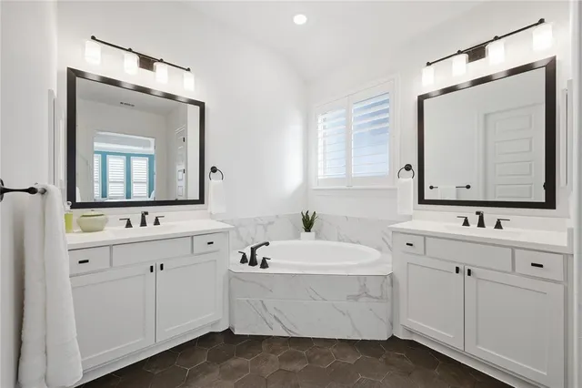 a bathroom with a double vanity sink mirror and bathtub
