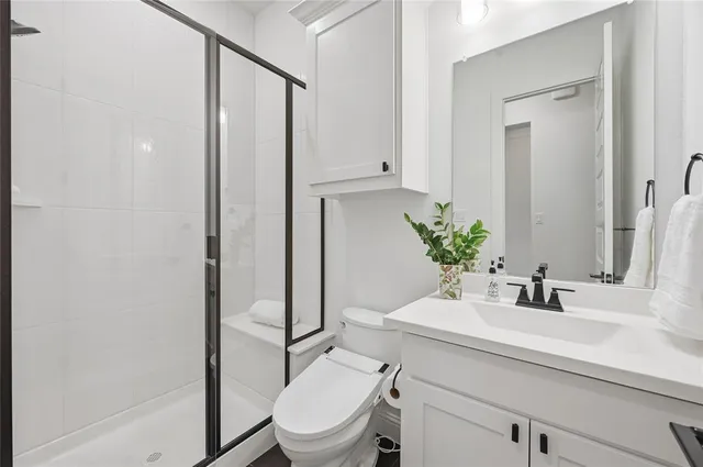 a bathroom with a sink a toilet a mirror and shower