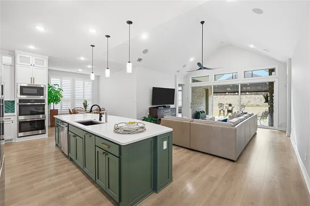 a large kitchen with stainless steel appliances kitchen island a large counter top a sink and a wooden floor