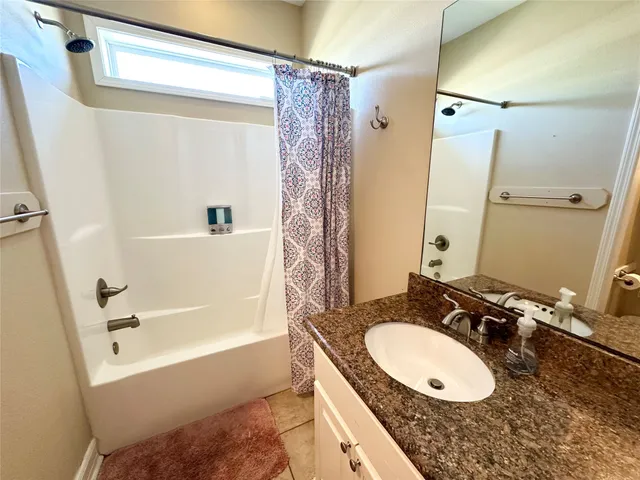 a bathroom with a granite countertop sink mirror vanity and a bathtub