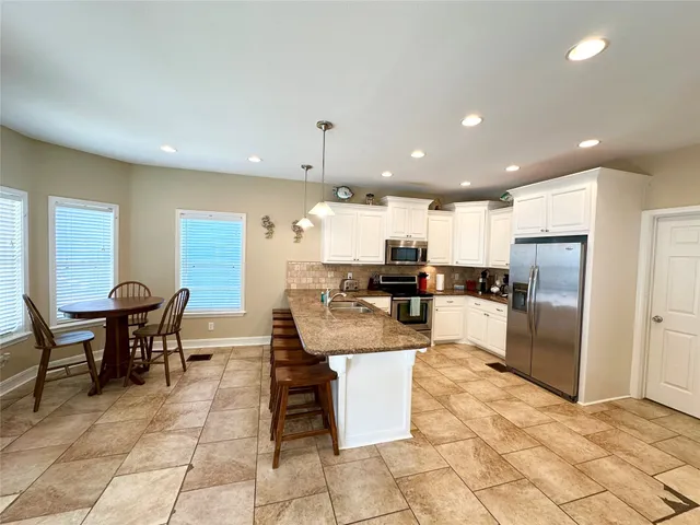 a kitchen with stainless steel appliances kitchen island granite countertop a sink a counter top space and cabinets