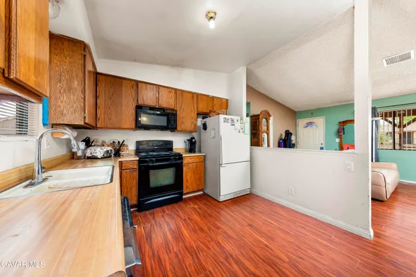 a kitchen with granite countertop wooden floors a refrigerator and a stove top oven