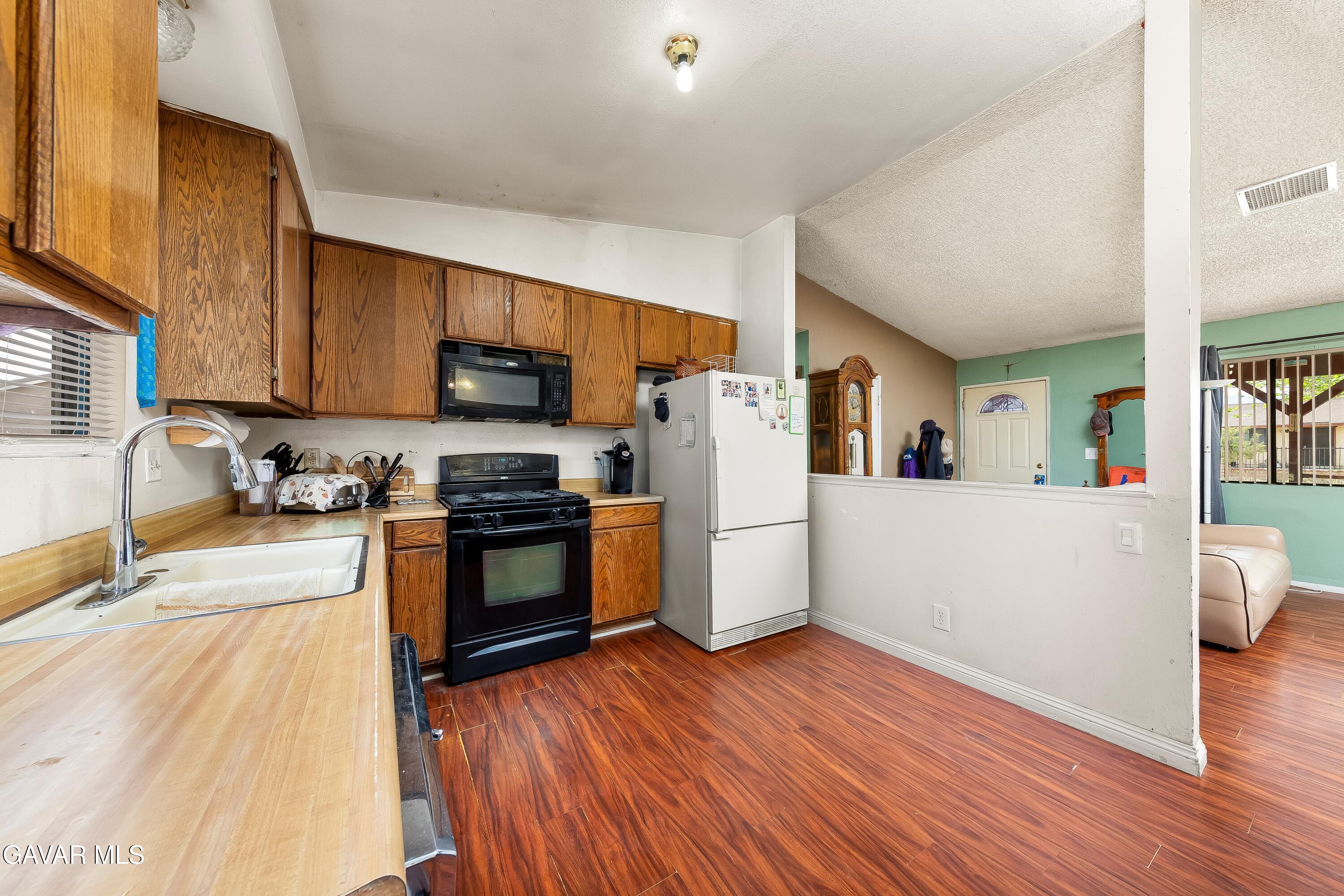 10731 East Ave R-2 Littlerock, CA 93543 - Photo 5 of 23 a kitchen with granite countertop wooden floors a refrigerator and a stove top oven