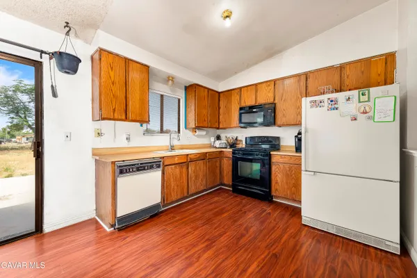 a kitchen with a refrigerator wooden floor a stove top oven a sink and a window