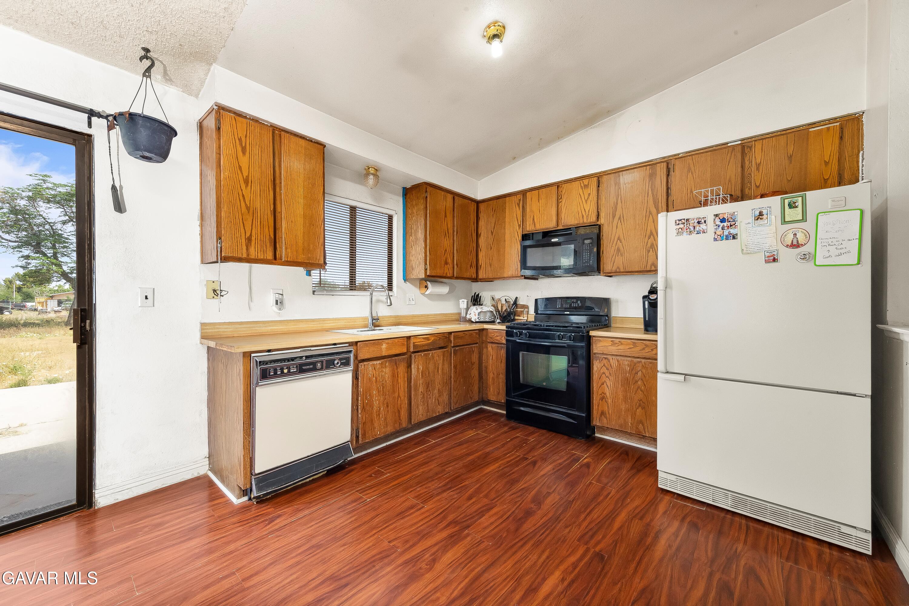 10731 East Ave R-2 Littlerock, CA 93543 - Photo 7 of 23 a kitchen with a refrigerator wooden floor a stove top oven a sink and a window