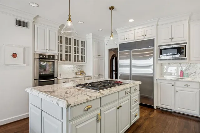 a kitchen with a stove a sink dishwasher a refrigerator and white cabinets with wooden floor