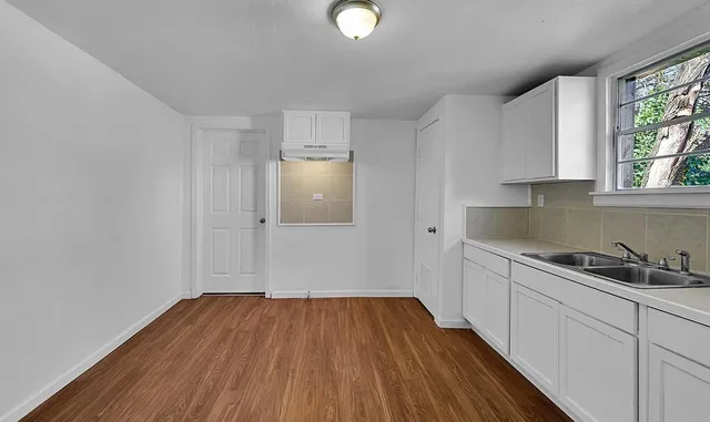 a kitchen with wooden floors and white walls