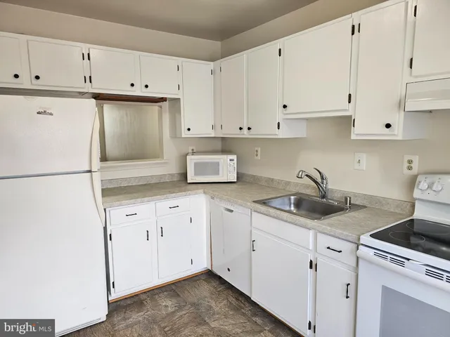 a kitchen with granite countertop white cabinets and white appliances