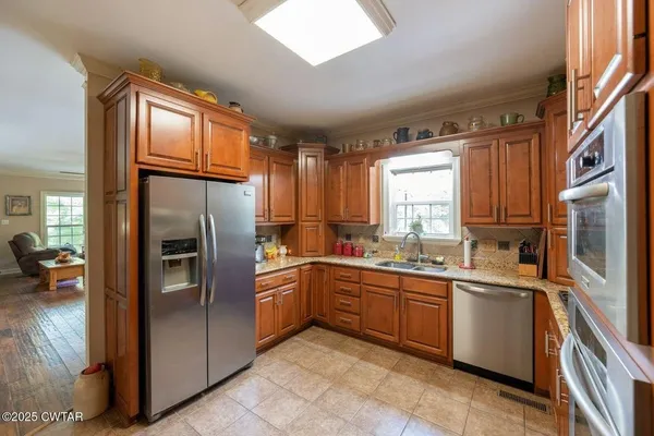 a kitchen with stainless steel appliances granite countertop a refrigerator a sink dishwasher a stove and a refrigerator
