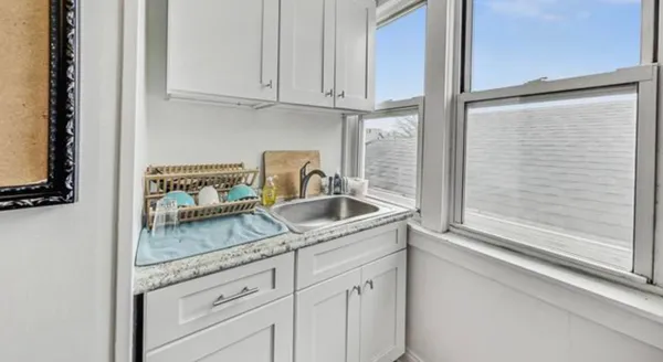 a kitchen with granite countertop white cabinets and a sink