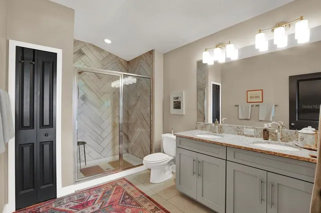 a spacious bathroom with a double vanity sink toilet mirror and shower