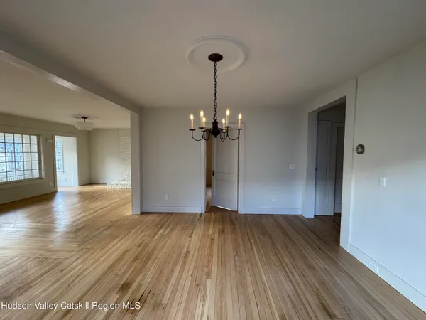 a view of a room with wooden floor chandelier and windows