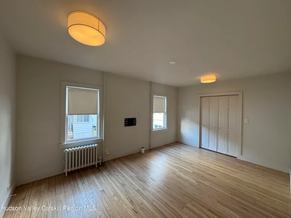 an empty room with wooden floor and windows