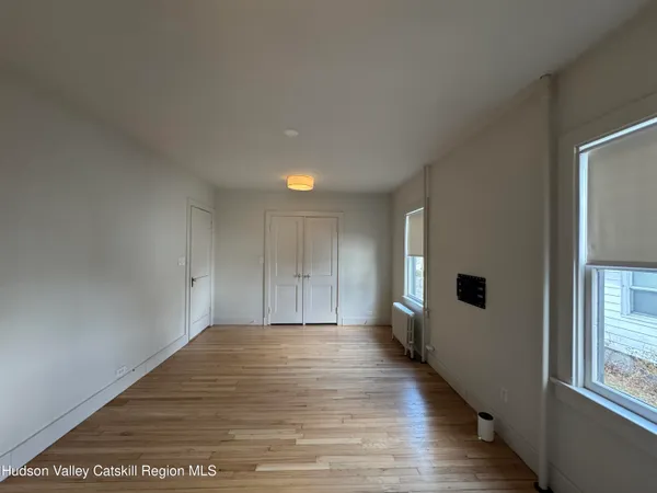 a view of an empty room with wooden floor and a window