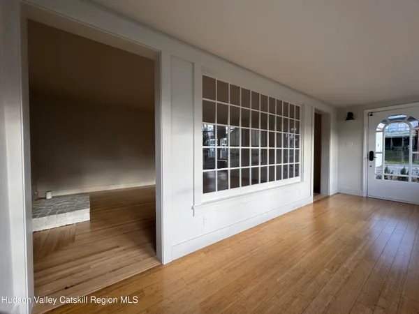 a view of an empty room with wooden floor and a window