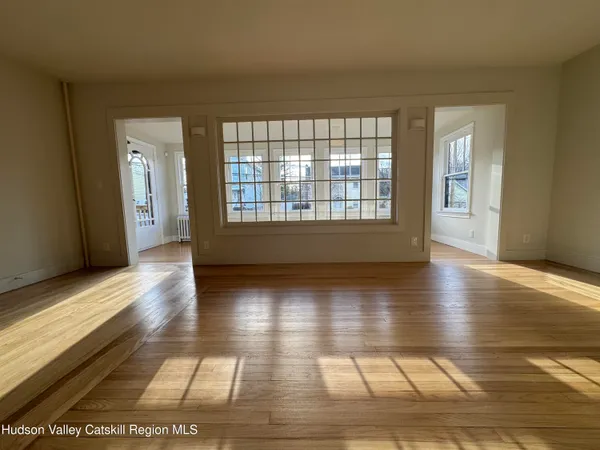 a view of an empty room with window and wooden floor