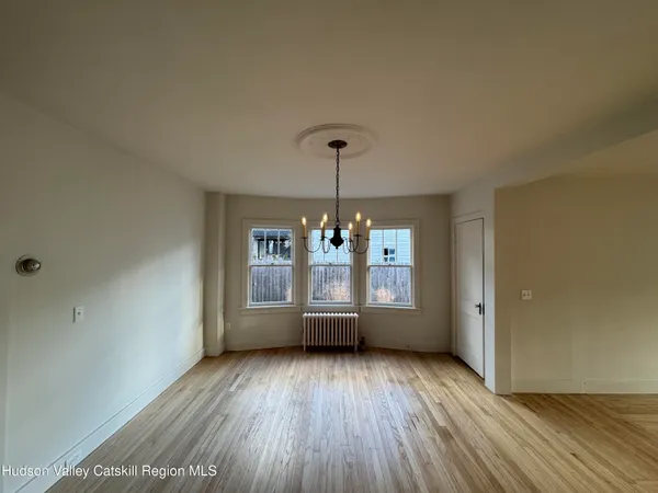 a view of an empty room with window and wooden floor