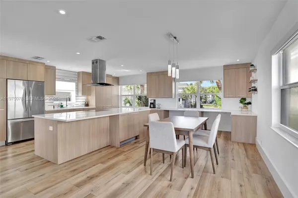 a kitchen with stainless steel appliances a refrigerator a sink a stove and white cabinets with wooden floor