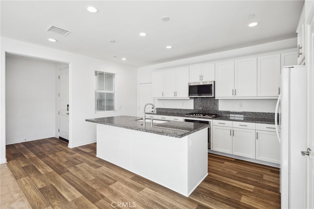 45037 Via Vela Temecula, CA 92592 - Photo 5 of 38 a large kitchen with granite countertop a sink and dishwasher a stove top oven with wooden floor