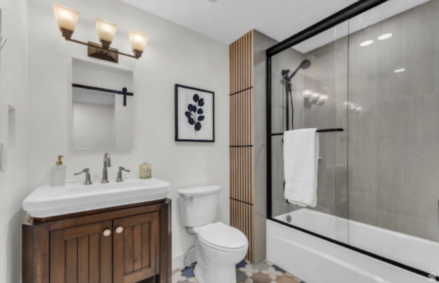 88 West 50 South, Unit C8 Centerville, UT 84014 - Photo 17 of 29 Bathroom featuring a wood-finish vanity with an integrated sink, a contemporary toilet, and a bathtub with a sliding glass enclosure