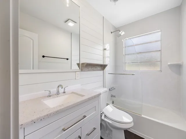 a bathroom with a granite countertop sink a toilet and a bathtub