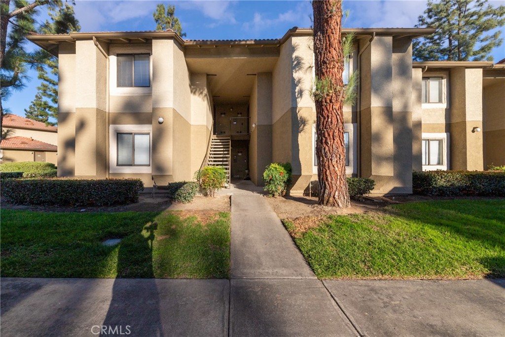 10151 Arrow Route, Unit 74 Rancho Cucamonga, CA 91730 - Photo 1 of 1 a view of a house with brick walls and a yard with plants