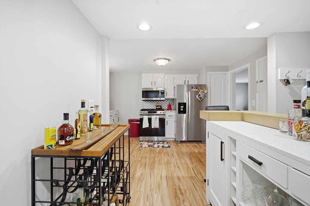 13 Bither Street Springfield, MA 01118 - Photo 13 of 29 a kitchen with stainless steel appliances kitchen island granite countertop a refrigerator a stove a sink dishwasher and a dining table with wooden floor