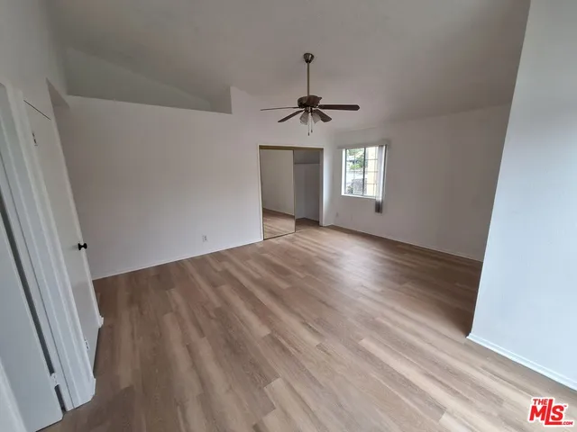 a view of empty room with wooden floor and ceiling fan