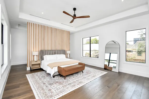 a spacious bedroom with a bed a dresser and wooden floor