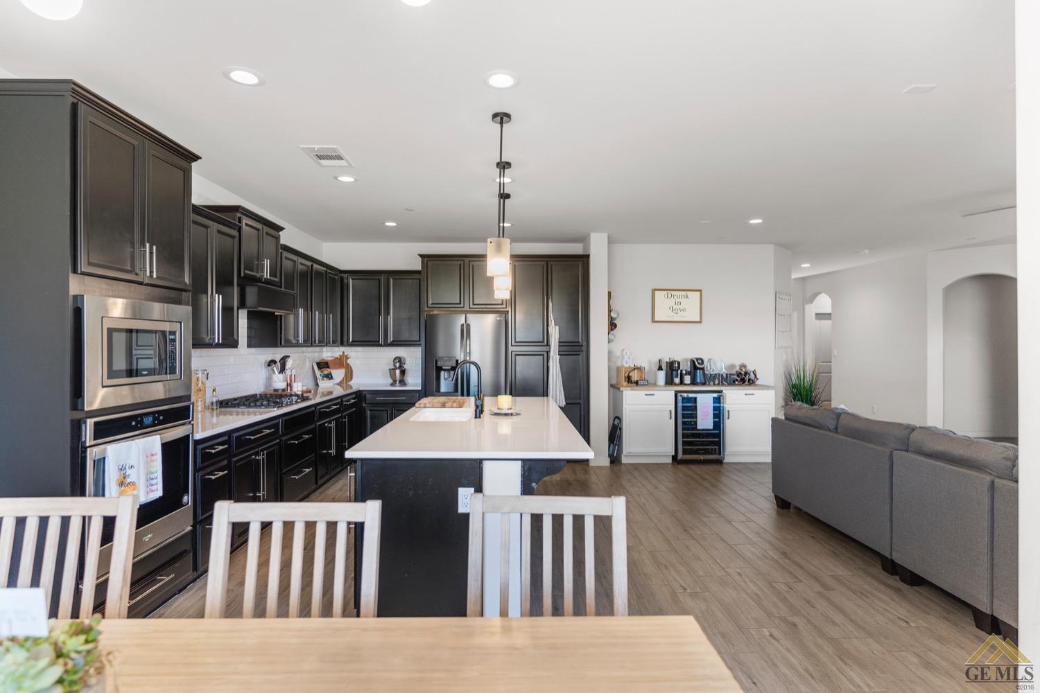 Undisclosed Address Bakersfield, CA 93314 - Photo 11 of 44 a kitchen with stainless steel appliances kitchen island granite countertop a refrigerator a sink dishwasher a dining table and chairs with wooden floor