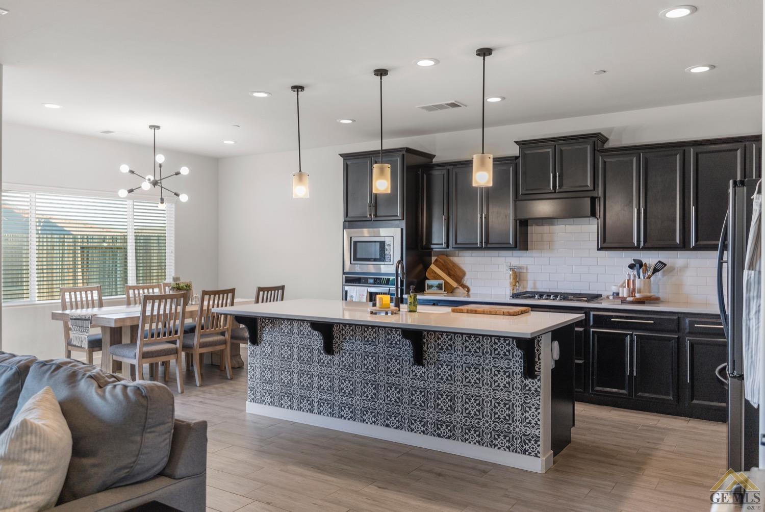 Undisclosed Address Bakersfield, CA 93314 - Photo 15 of 44 a kitchen with stainless steel appliances granite countertop a stove top oven a sink dishwasher a dining table and chairs with wooden floor