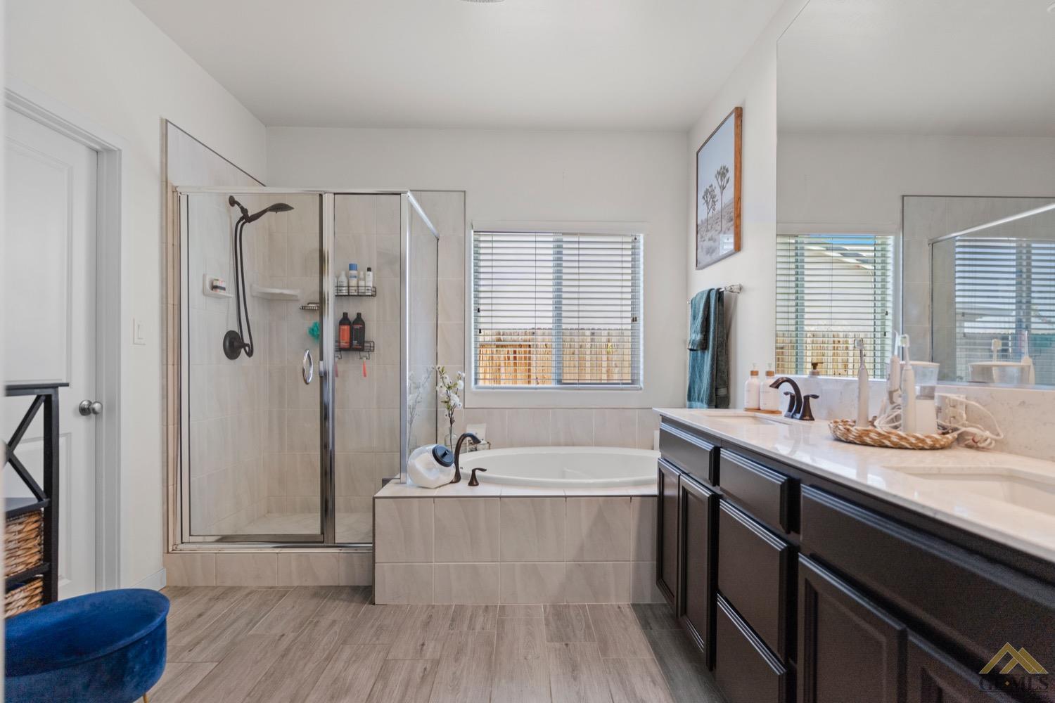 Undisclosed Address Bakersfield, CA 93314 - Photo 30 of 44 a bathroom with a double vanity sink a mirror a bathtub and shower
