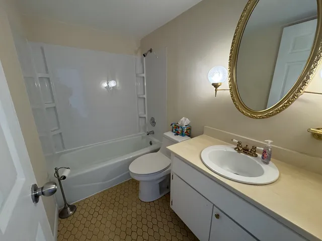 a view of a hallway with wooden floor and a bathroom