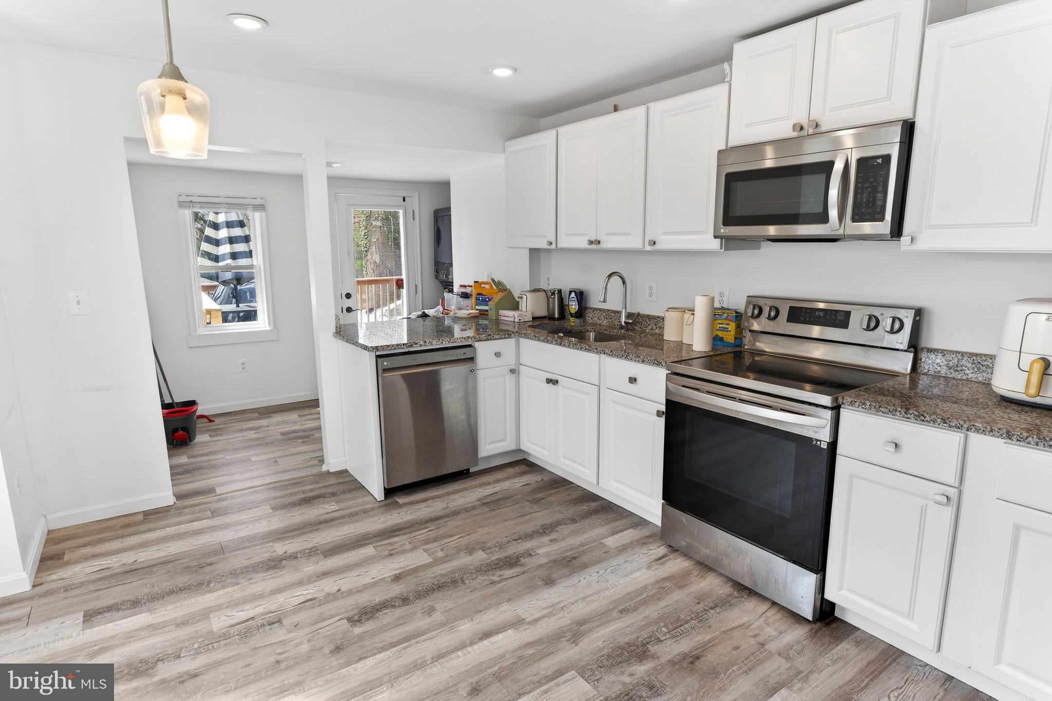1002 West Main Street Salisbury, MD 21801 - Photo 16 of 31 a kitchen with stainless steel appliances granite countertop a stove top oven a sink dishwasher and a microwave oven with wooden floor