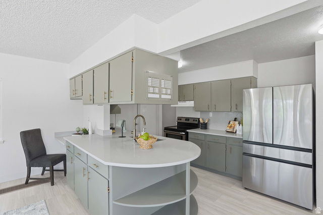6889 South Village Road Salt Lake City, UT 84121 - Photo 13 of 44 Modern kitchen featuring an expansive central island with an integrated sink and gooseneck faucet