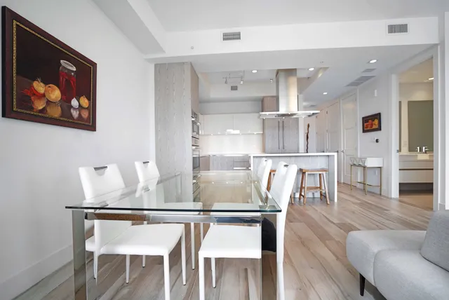 a kitchen with stainless steel appliances granite countertop a dining table chairs and view of living room