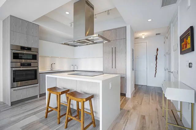 a kitchen with kitchen island stainless steel appliances a stove cabinets and wooden floor